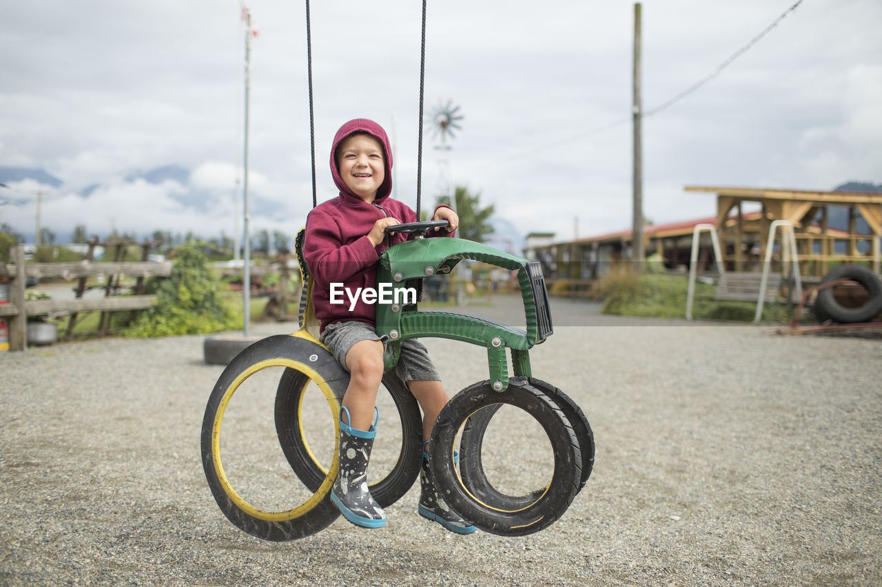 Happy boy sits on play ride on tractor made from recycled tires