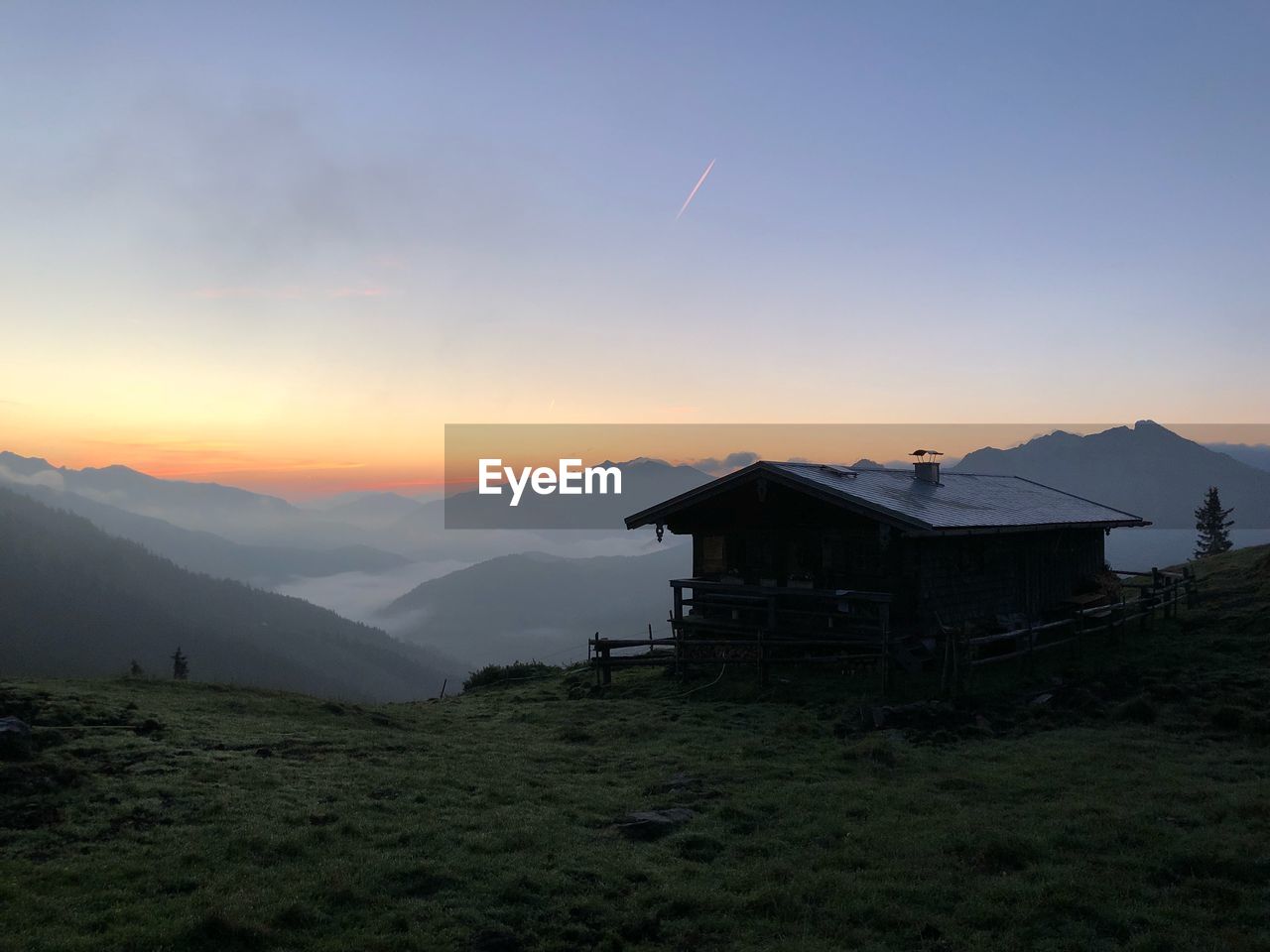 House on mountain against sky during sunset