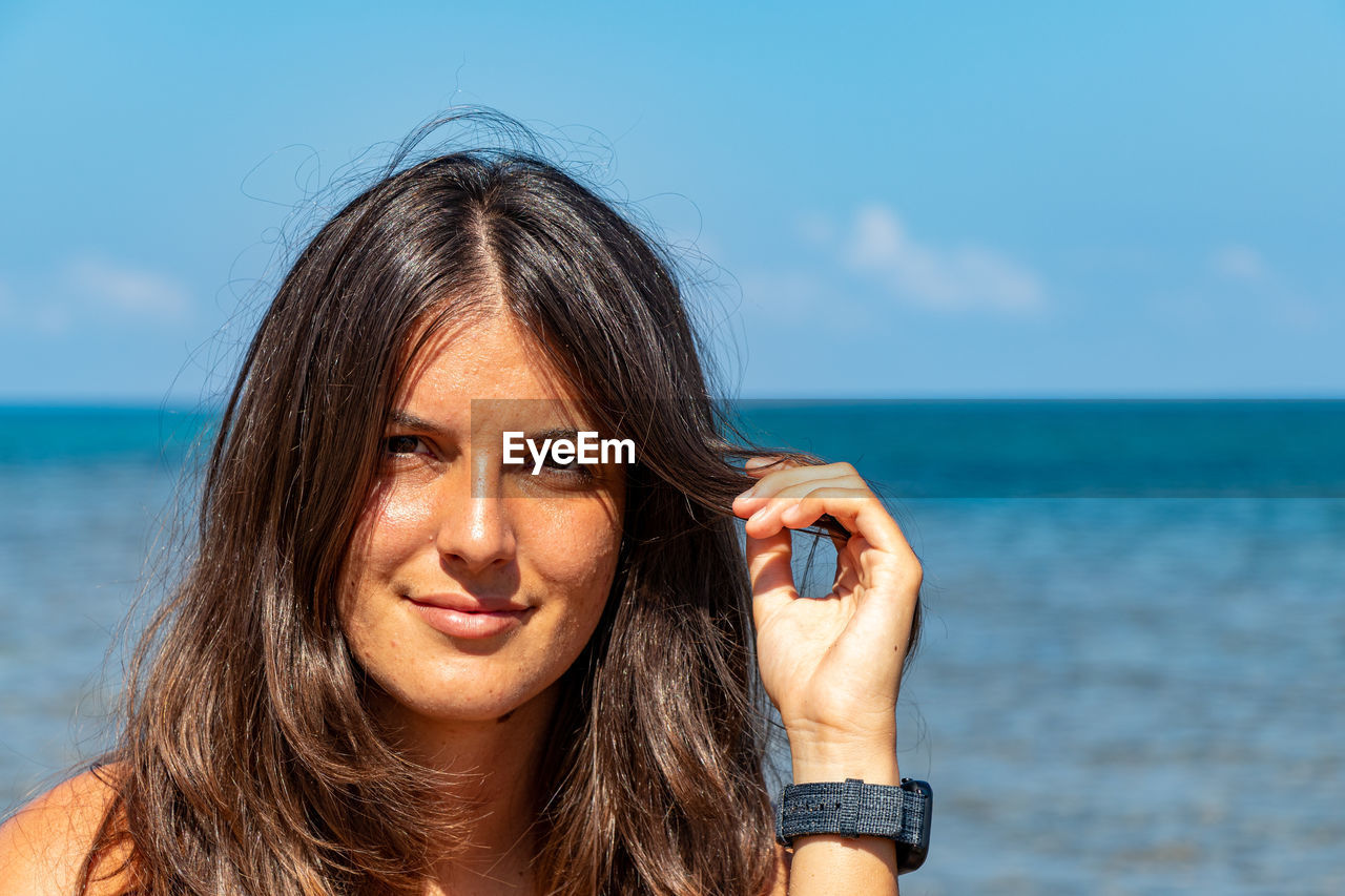 Portrait of woman at beach against sky in castelsardo