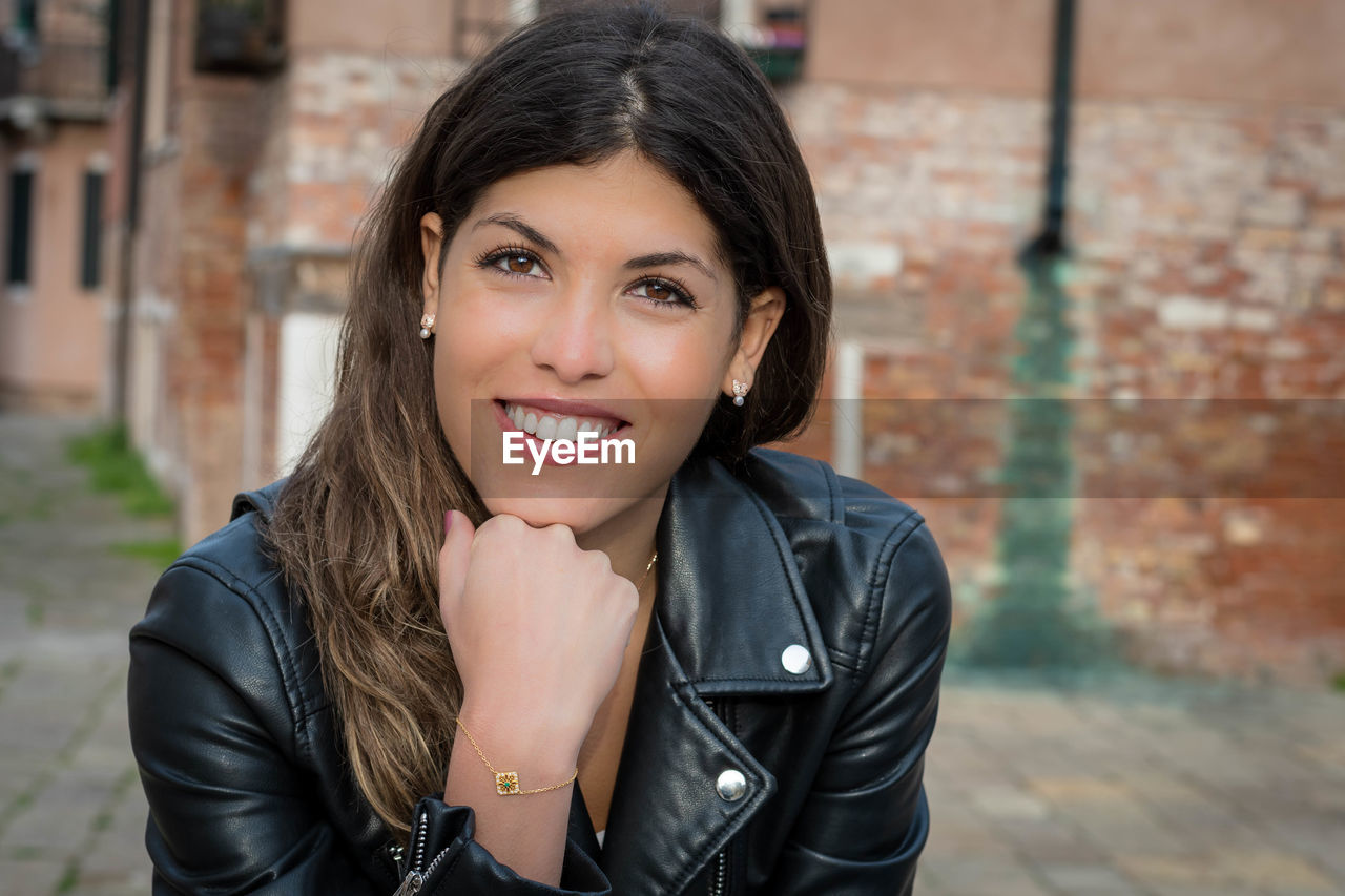 Portrait of smiling young woman against old building