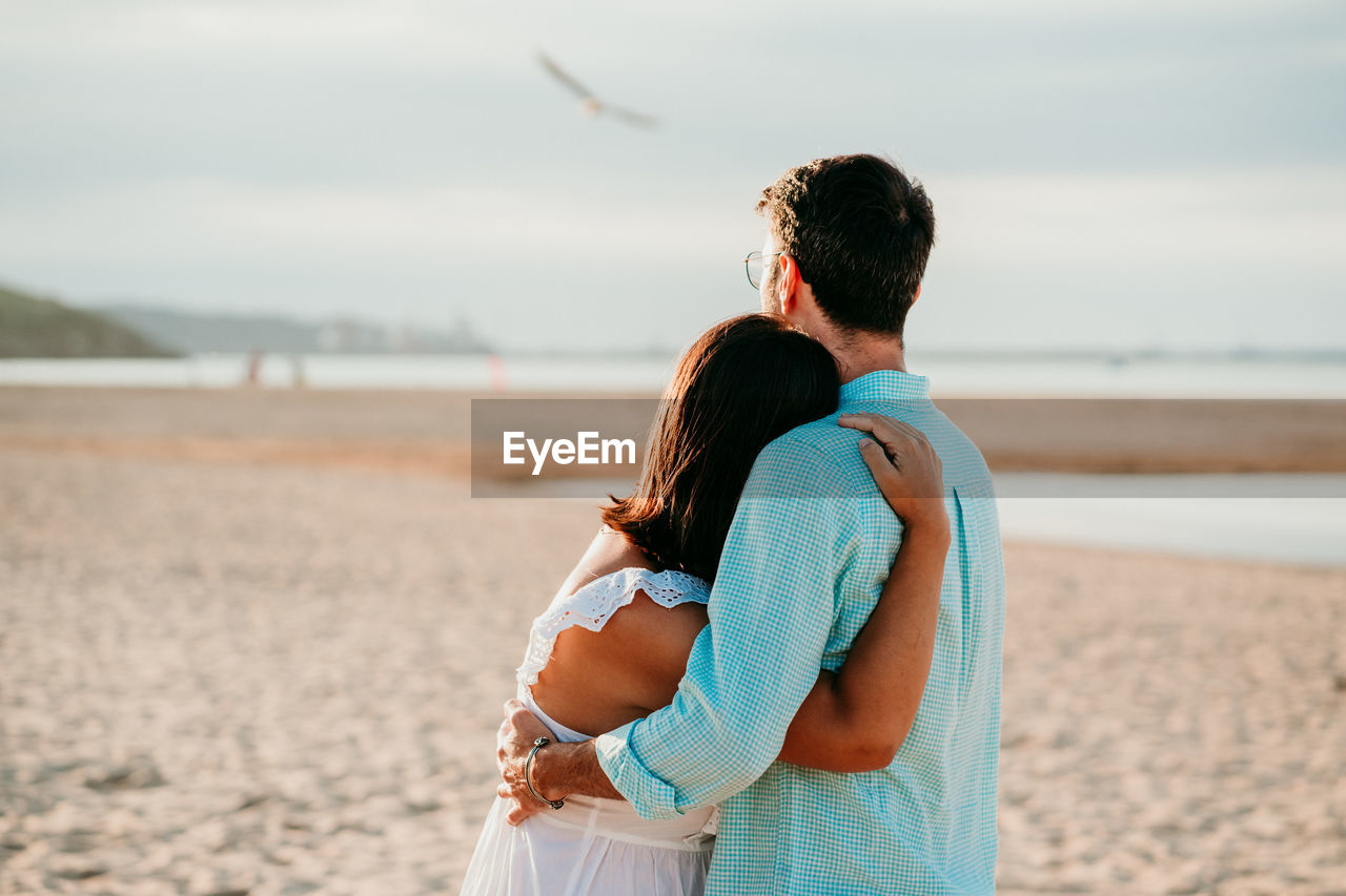 Couple embracing while standing on beach