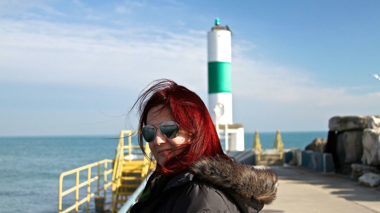 Portrait of woman wearing sunglasses standing at lighthouse