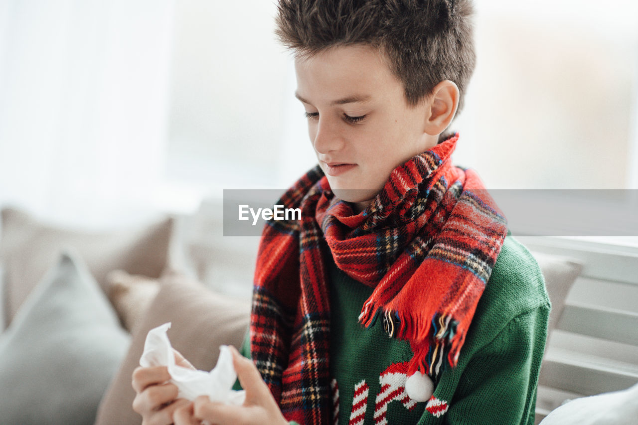 Smiling boy holding tissue sitting at home