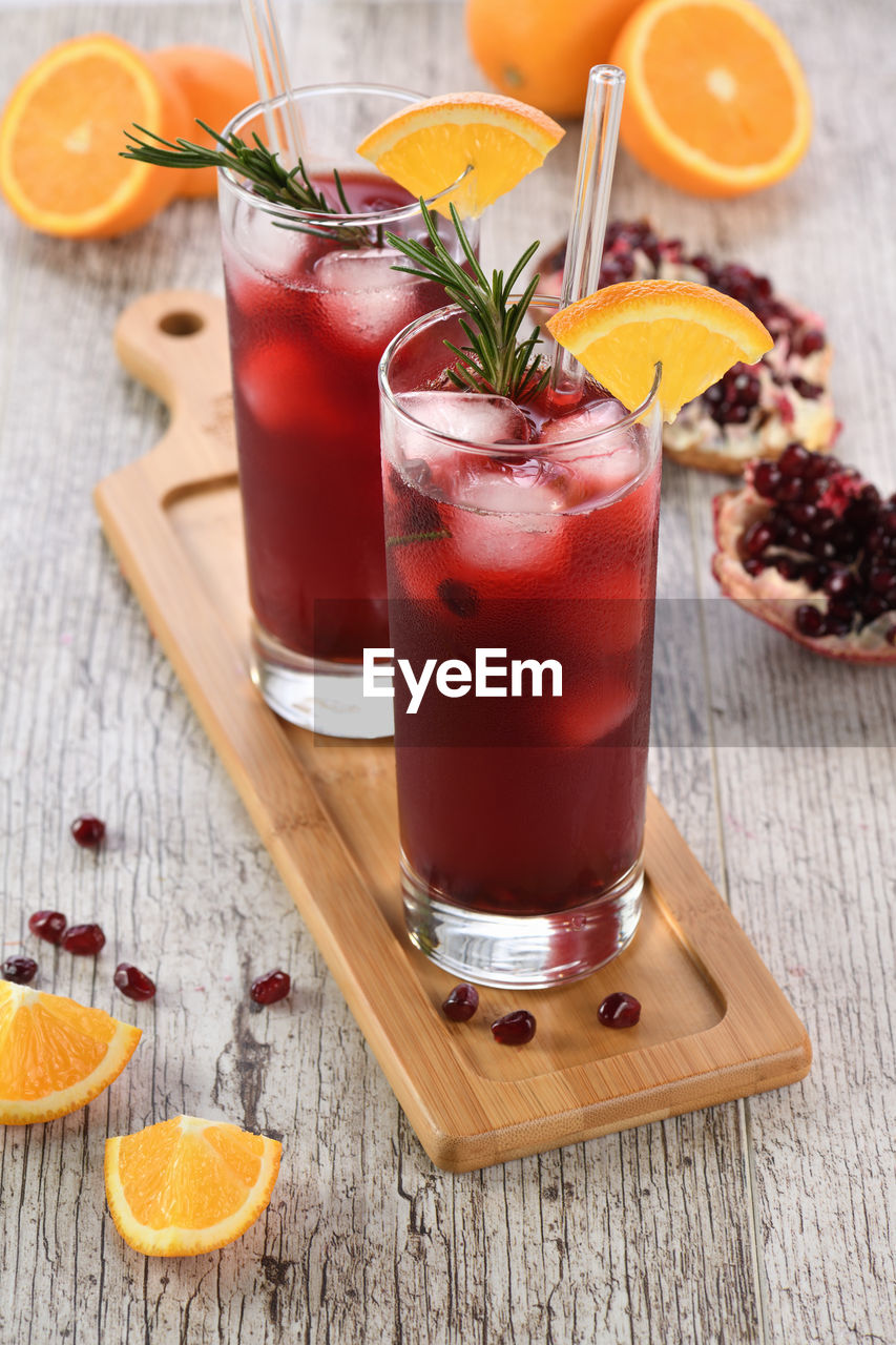 Pomegranate orange holiday punch with ice and rosemary. 