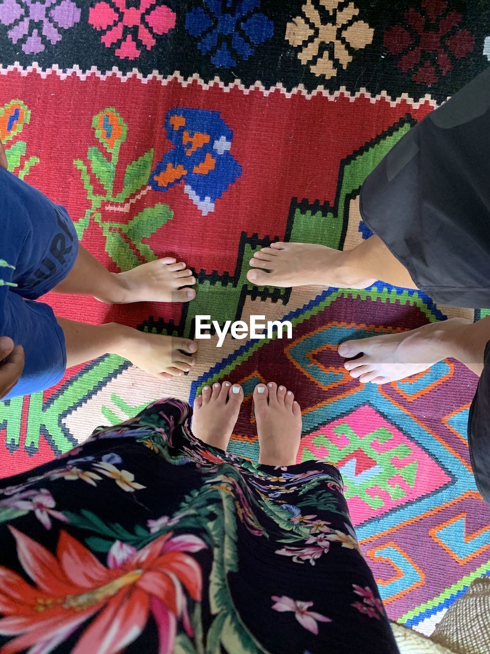 HIGH ANGLE VIEW OF PEOPLE ON MULTI COLORED CARPET