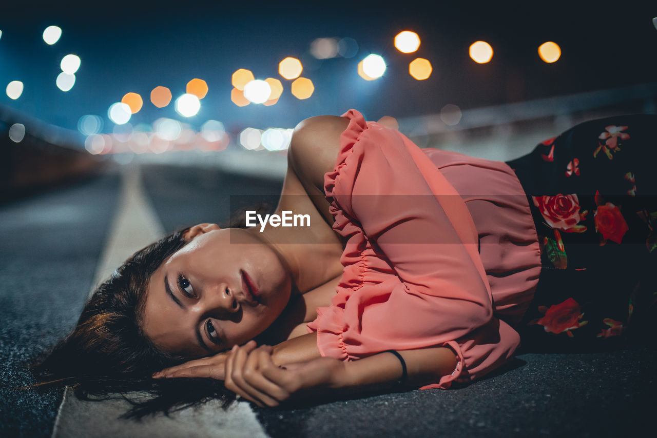 Young woman lying on road at night