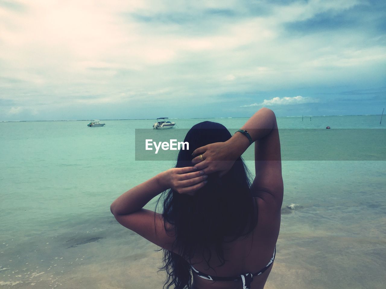 Woman standing at beach against sky