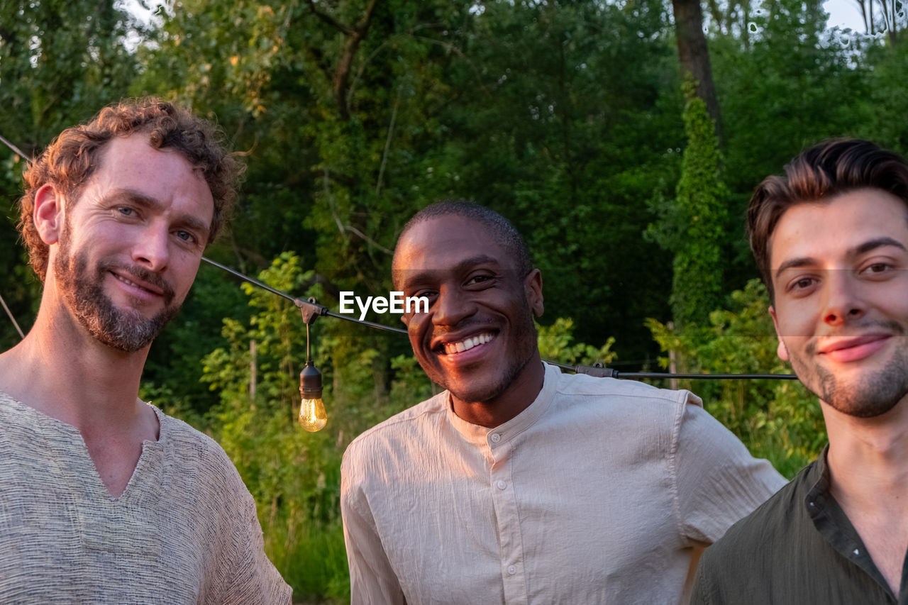 portrait of smiling friends standing in forest