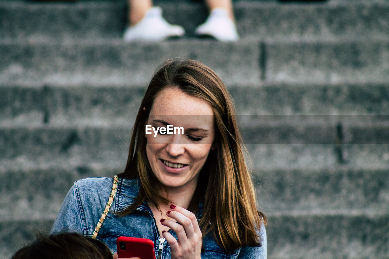 PORTRAIT OF YOUNG WOMAN USING MOBILE PHONE