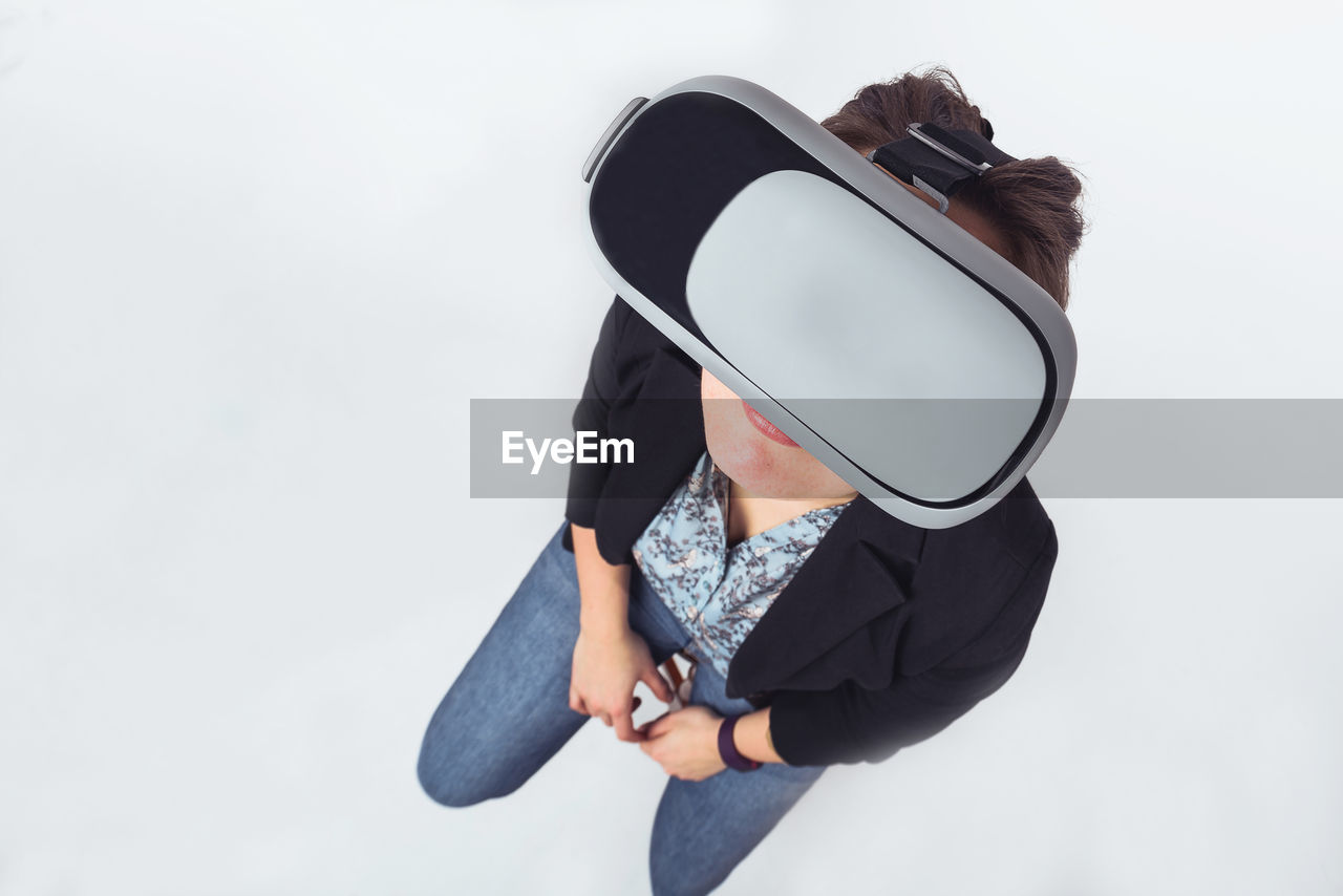 Woman using vr glasses while standing against gray background