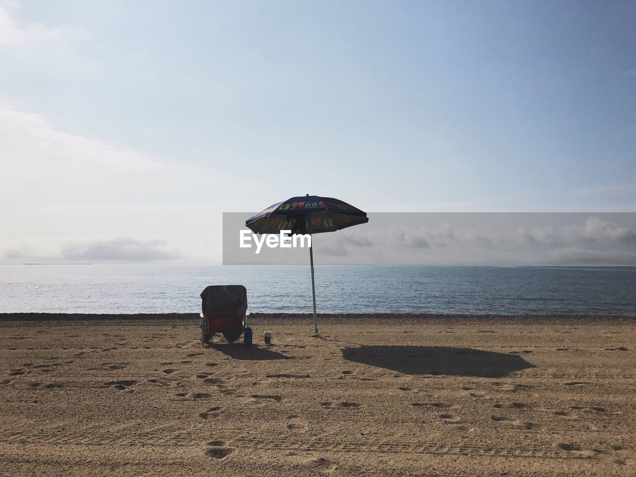 Parasol on sand at beach against sky