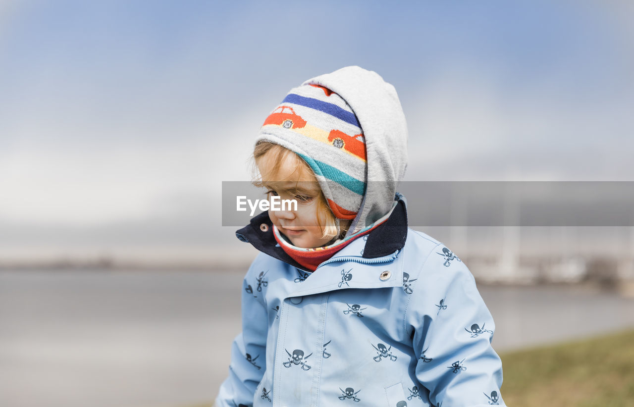 Close-up of girl wearing warm clothes while standing against sky during winter