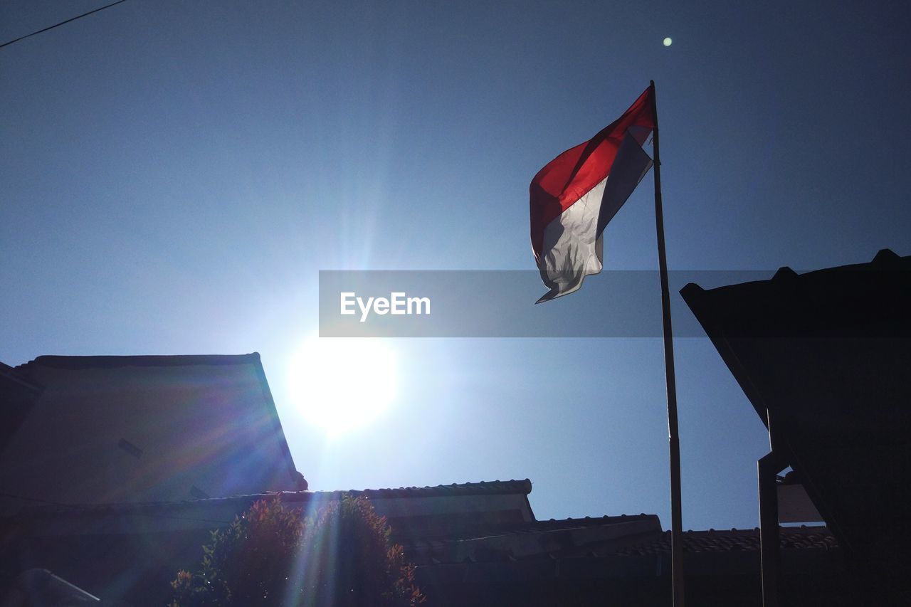 LOW ANGLE VIEW OF FLAG AGAINST BRIGHT SUN