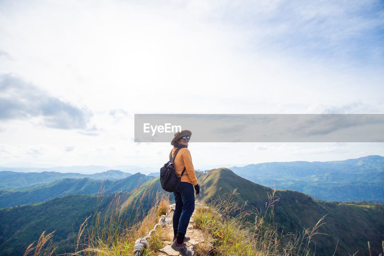 MAN STANDING ON MOUNTAINS AGAINST SKY