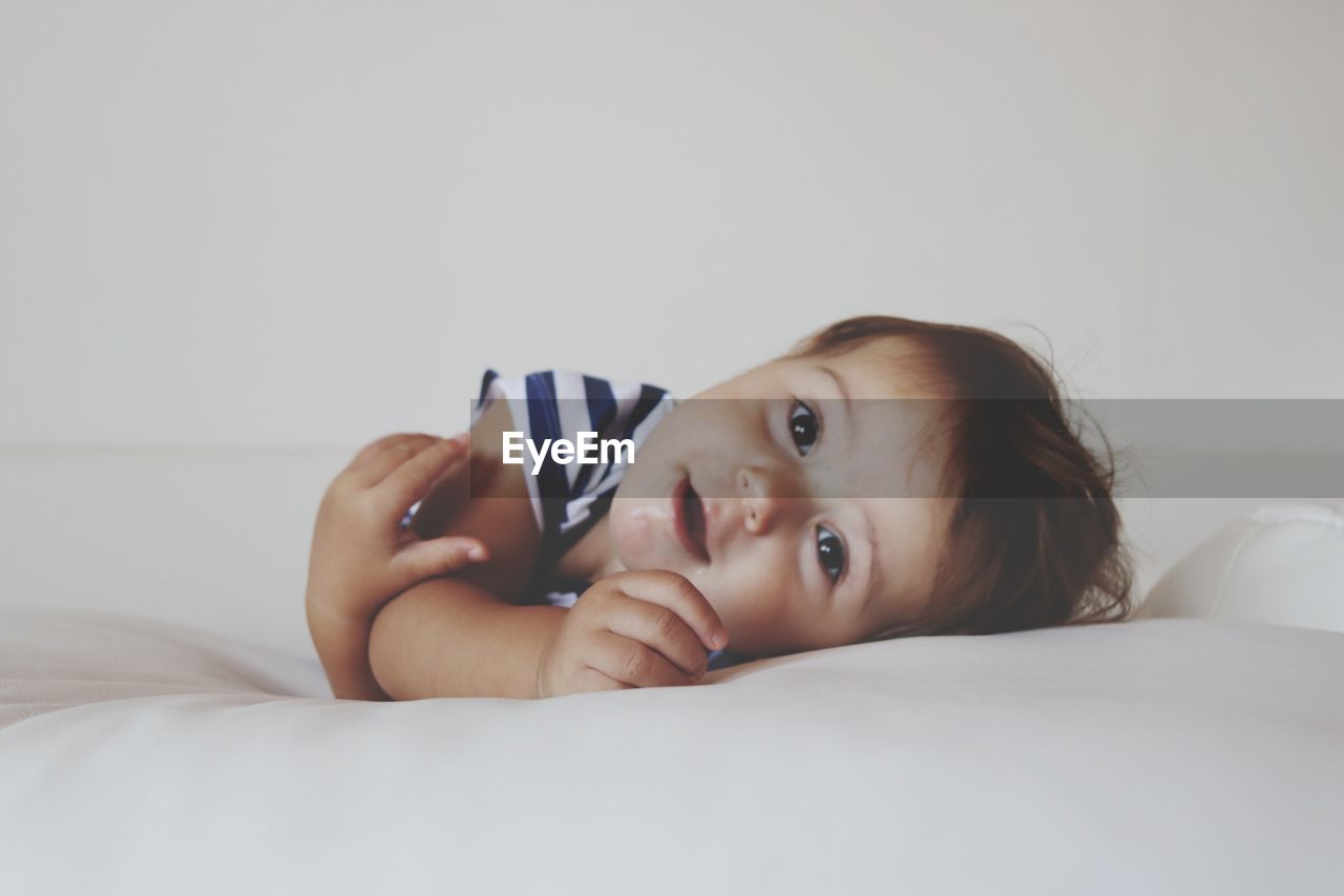 Portrait of cute baby girl lying on bed at home