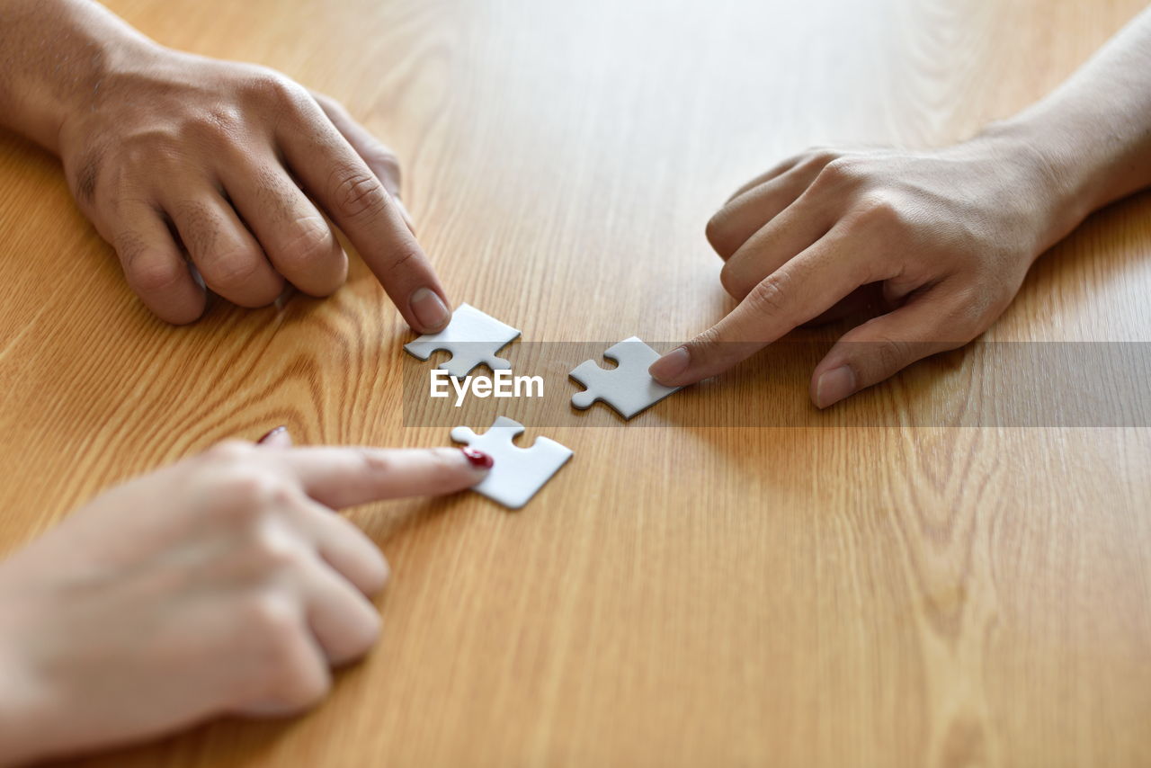 Cropped hands playing jigsaw puzzle at table