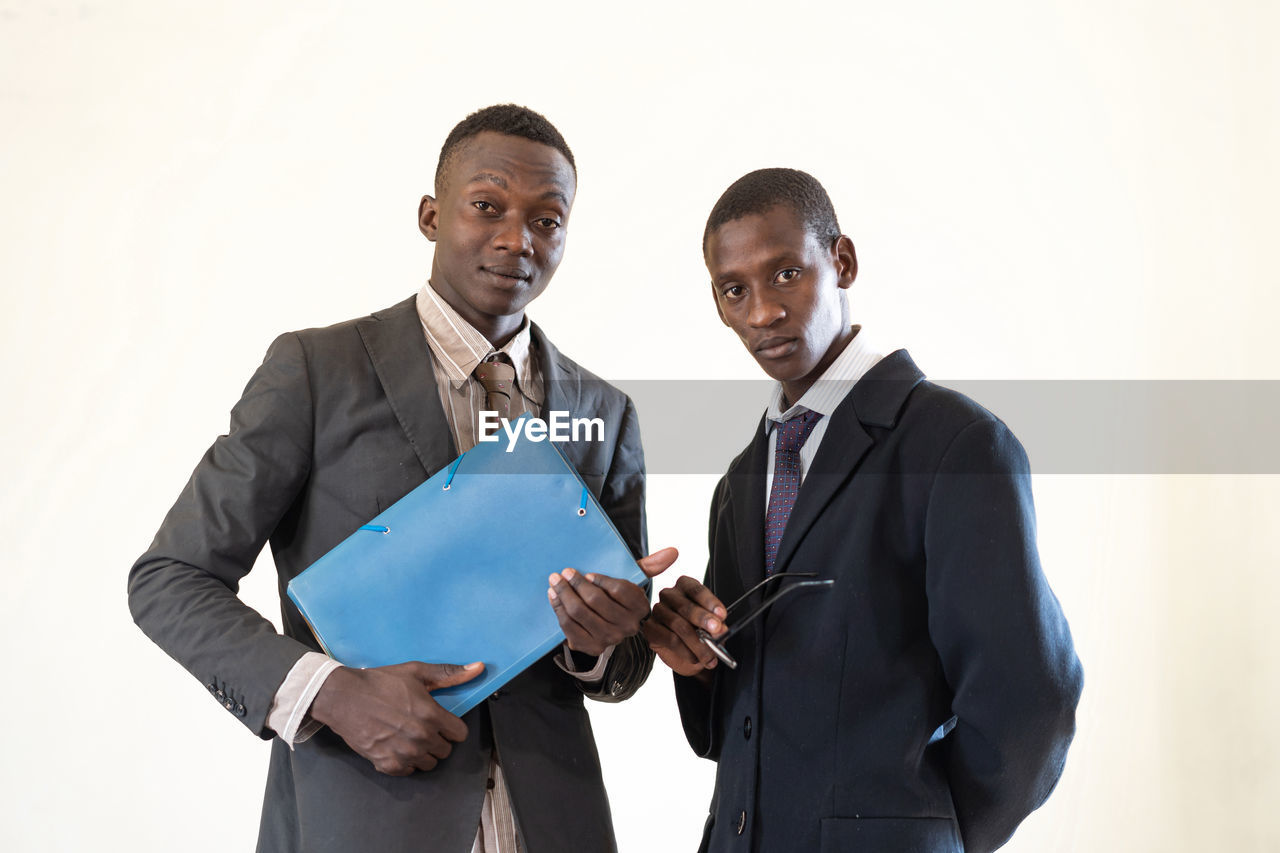 Portrait of male colleagues standing against white background