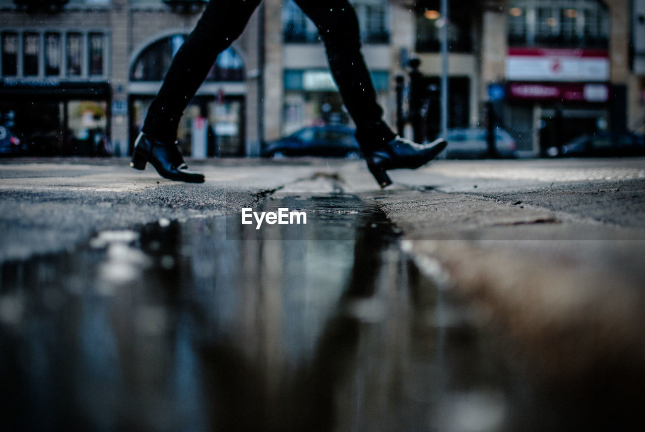 Low section of woman walking on wet street