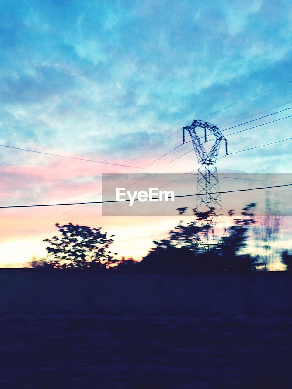 SILHOUETTE OF ELECTRICITY PYLON AGAINST SUNSET SKY