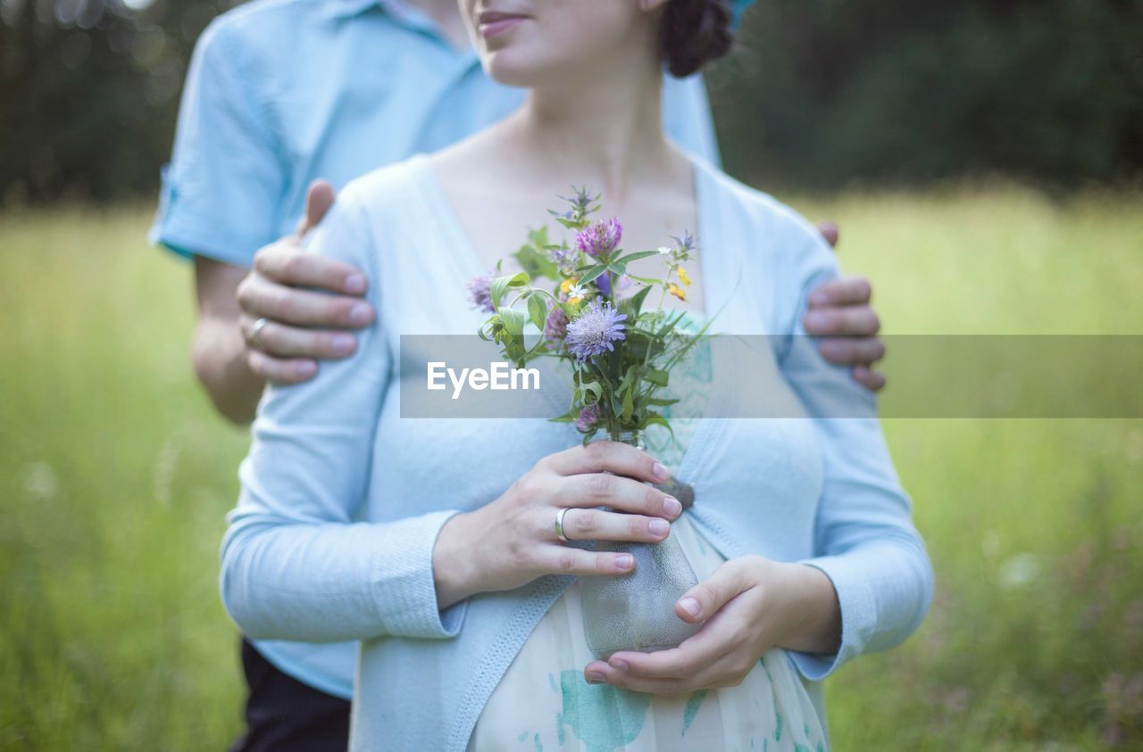 Midsection of couple standing on field