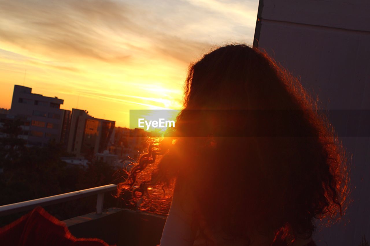 Rear view of woman against sky during sunset