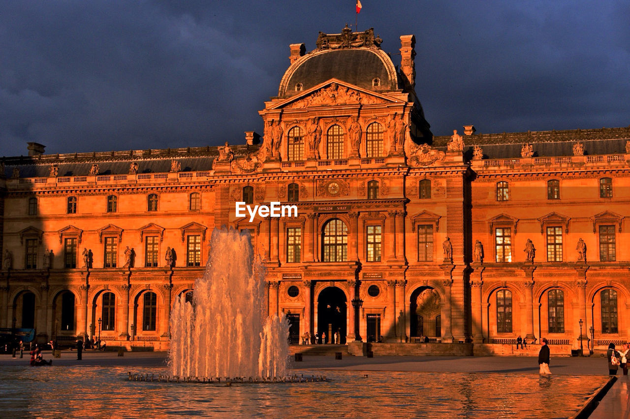 Exterior of louvre museum against cloudy sky