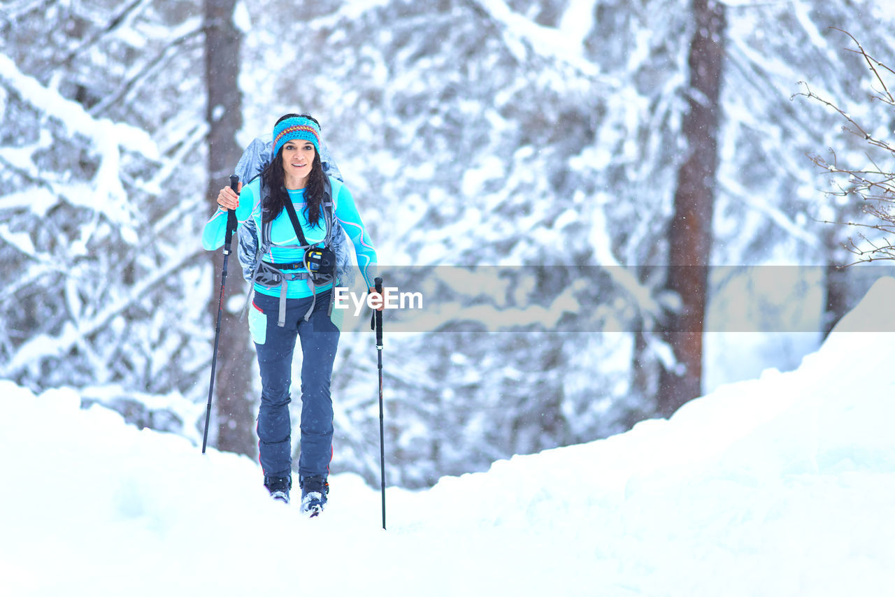 Young woman practicing ski touring during a snowfall in the woods