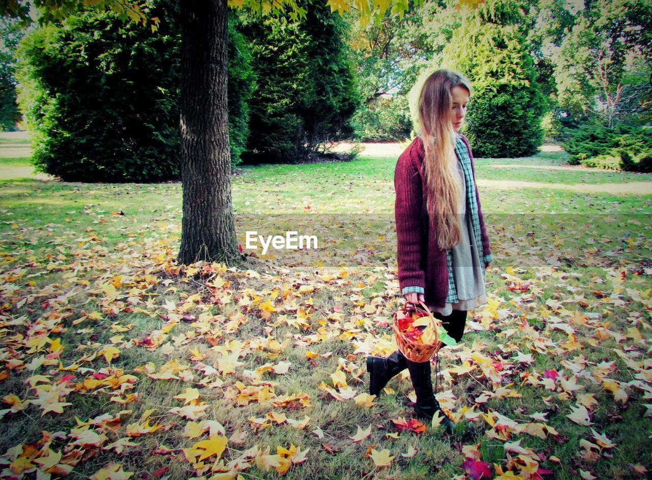 WOMAN STANDING BY TREE