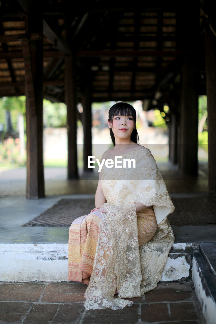 Full length of young woman sitting at temple