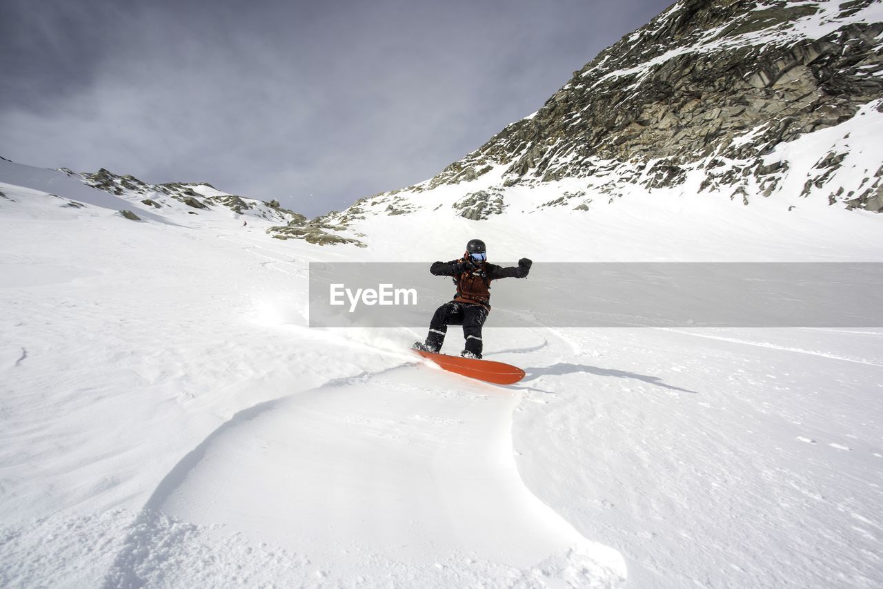 PERSON SKIING ON SNOWCAPPED MOUNTAIN AGAINST SKY