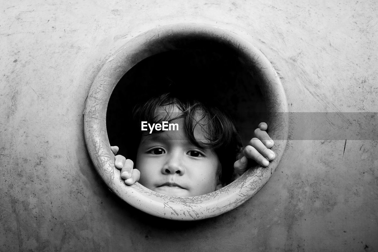 Close-up portrait of cute boy looking through circle at playground