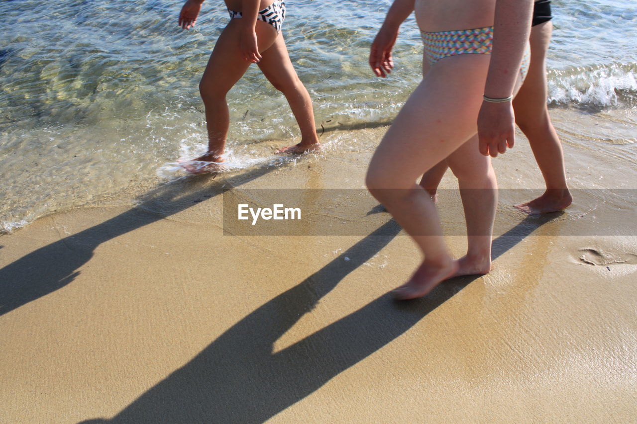 LOW SECTION OF FRIENDS ON SHORE AT BEACH