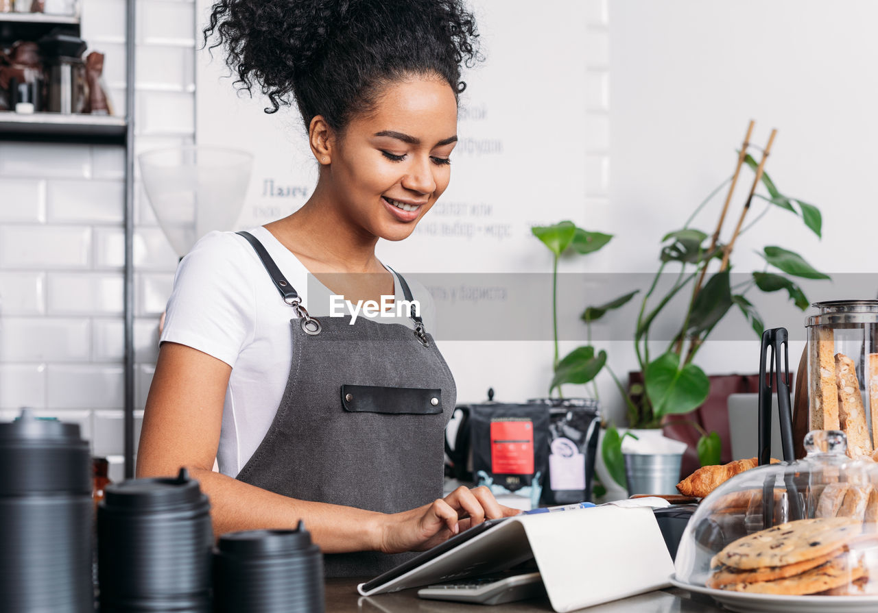 side view of young woman using mobile phone while sitting at home