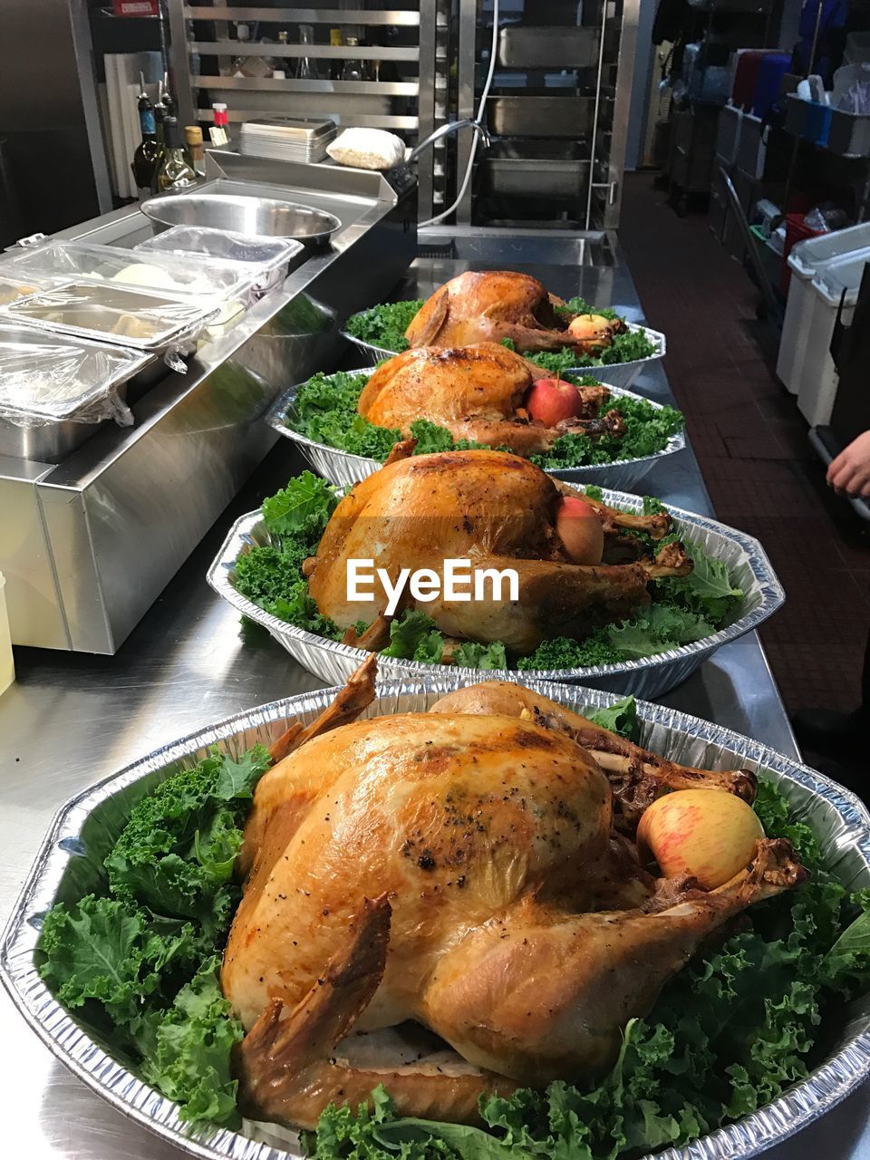 High angle view of roasted chickens in plates with lettuce and apples on kitchen counter at restaurant