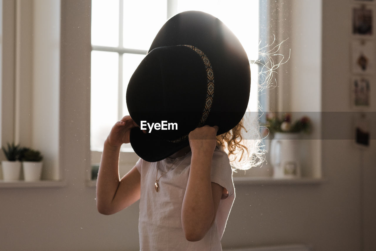 Portrait of a young girl playing with a hat covering her face