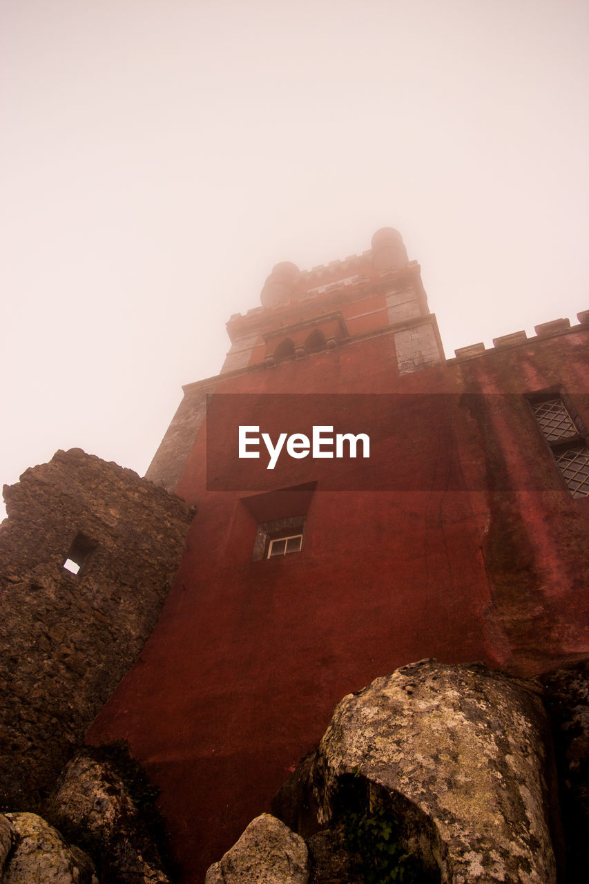 Low angle view of pena national palace against cloudy sky