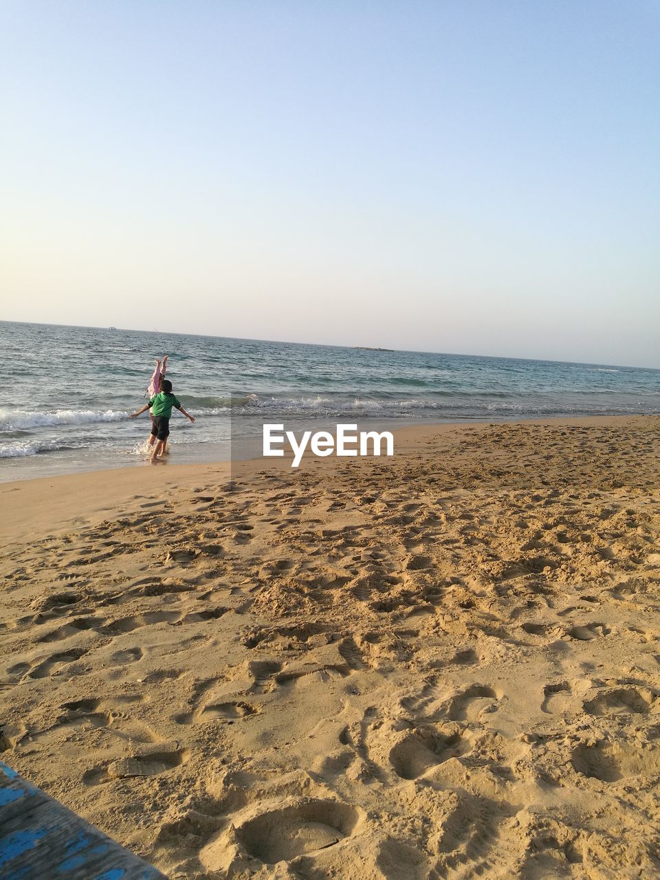 MAN AT BEACH AGAINST CLEAR SKY