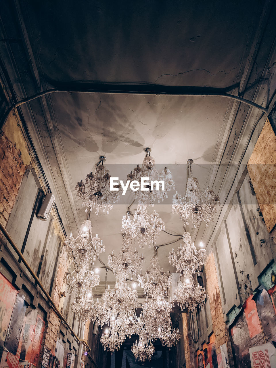 LOW ANGLE VIEW OF ILLUMINATED CHANDELIER HANGING FROM CEILING