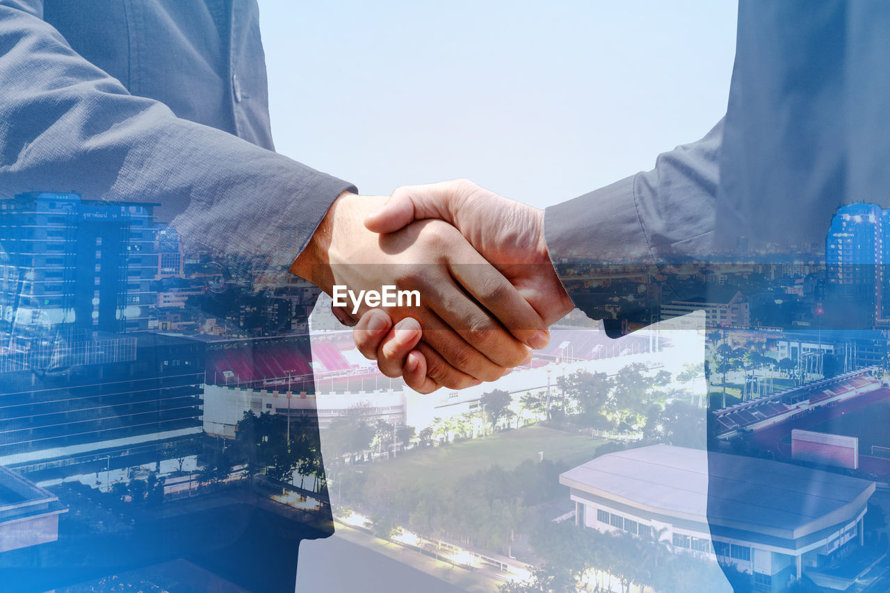 CROPPED IMAGE OF MAN HAND WITH CITYSCAPE