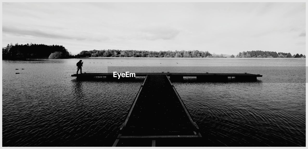 Man standing on pier over lake