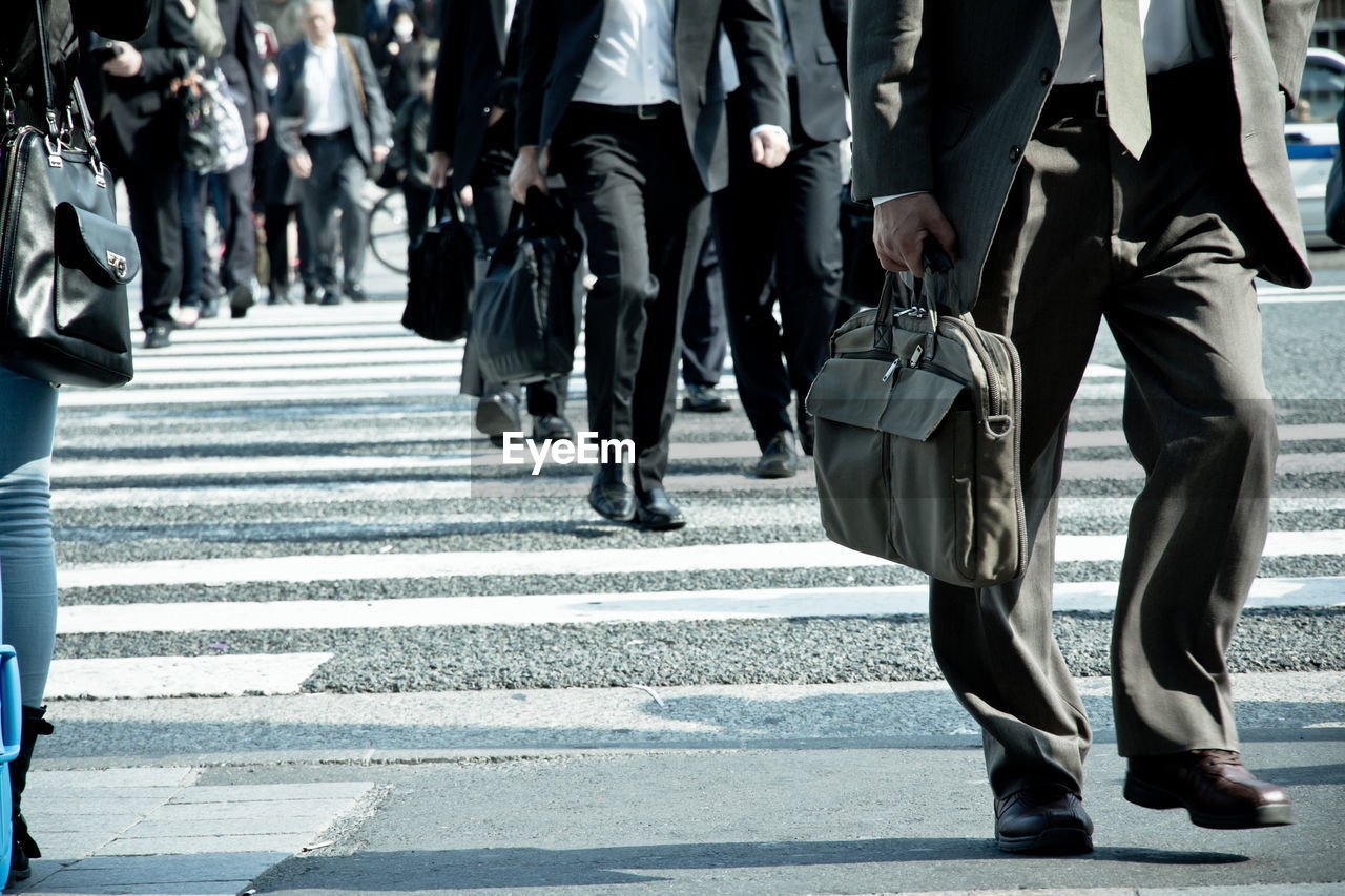 Low section of business people walking on road