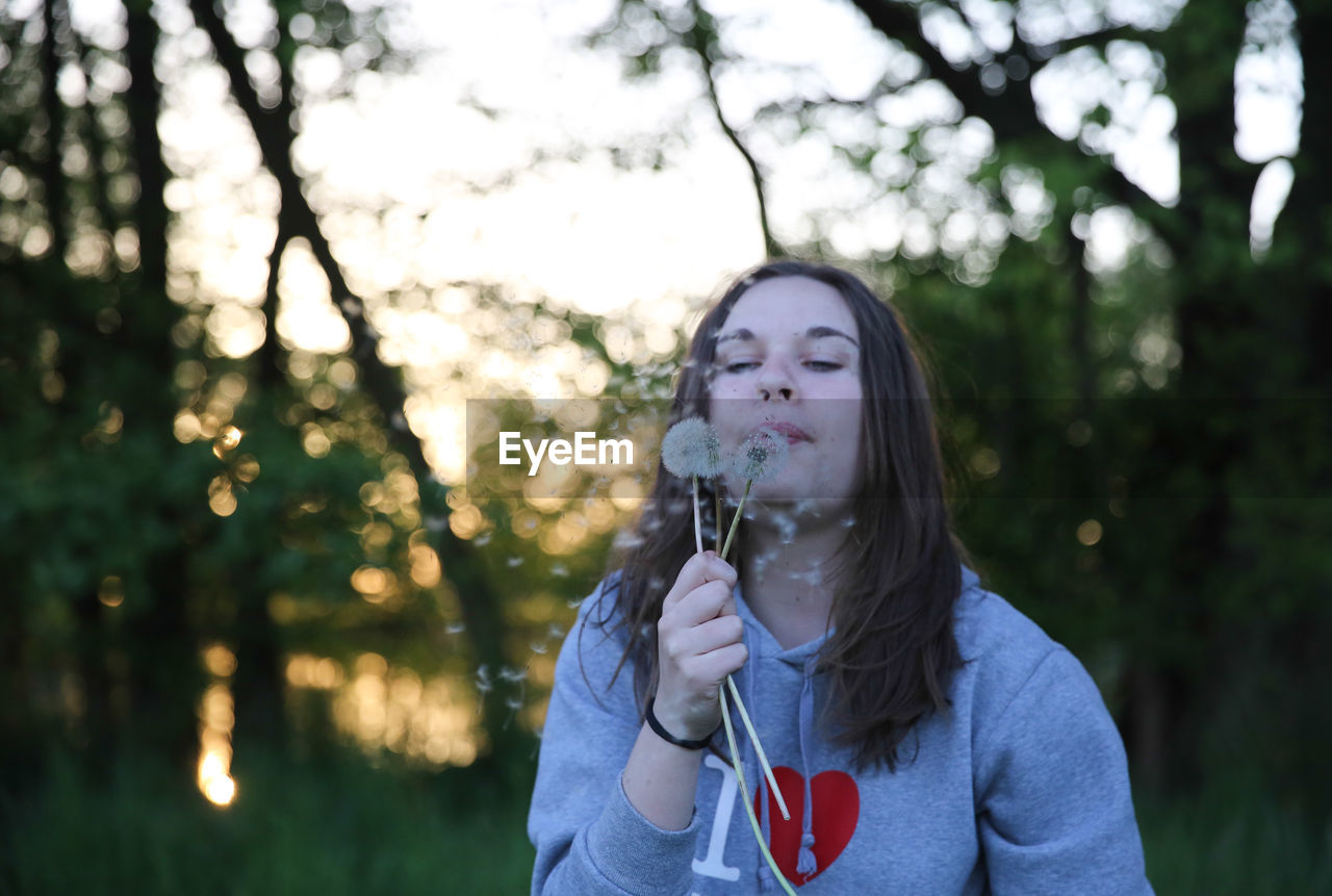 Close-up of a woman blowing dandelion