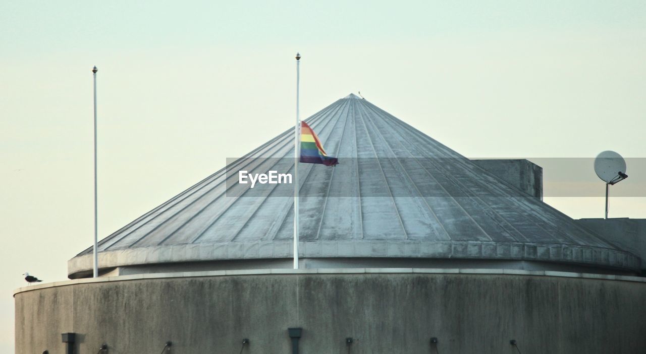 LOW ANGLE VIEW OF FLAG BY BUILDING AGAINST SKY