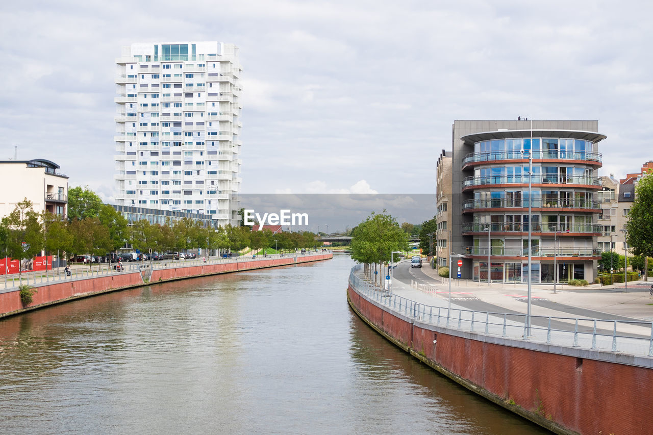 BUILDINGS BY RIVER AGAINST SKY