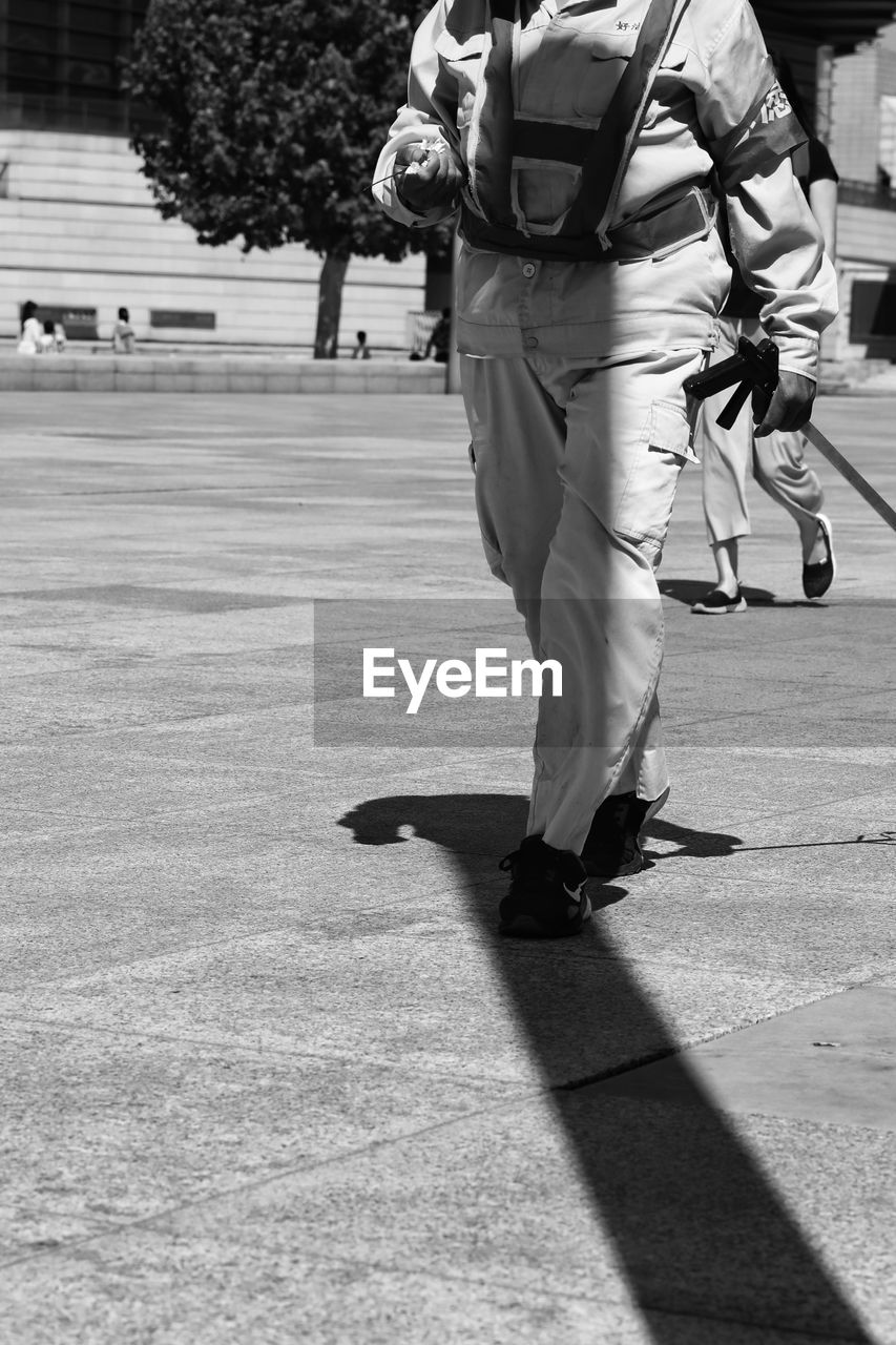 LOW SECTION OF MAN WALKING ON ROAD