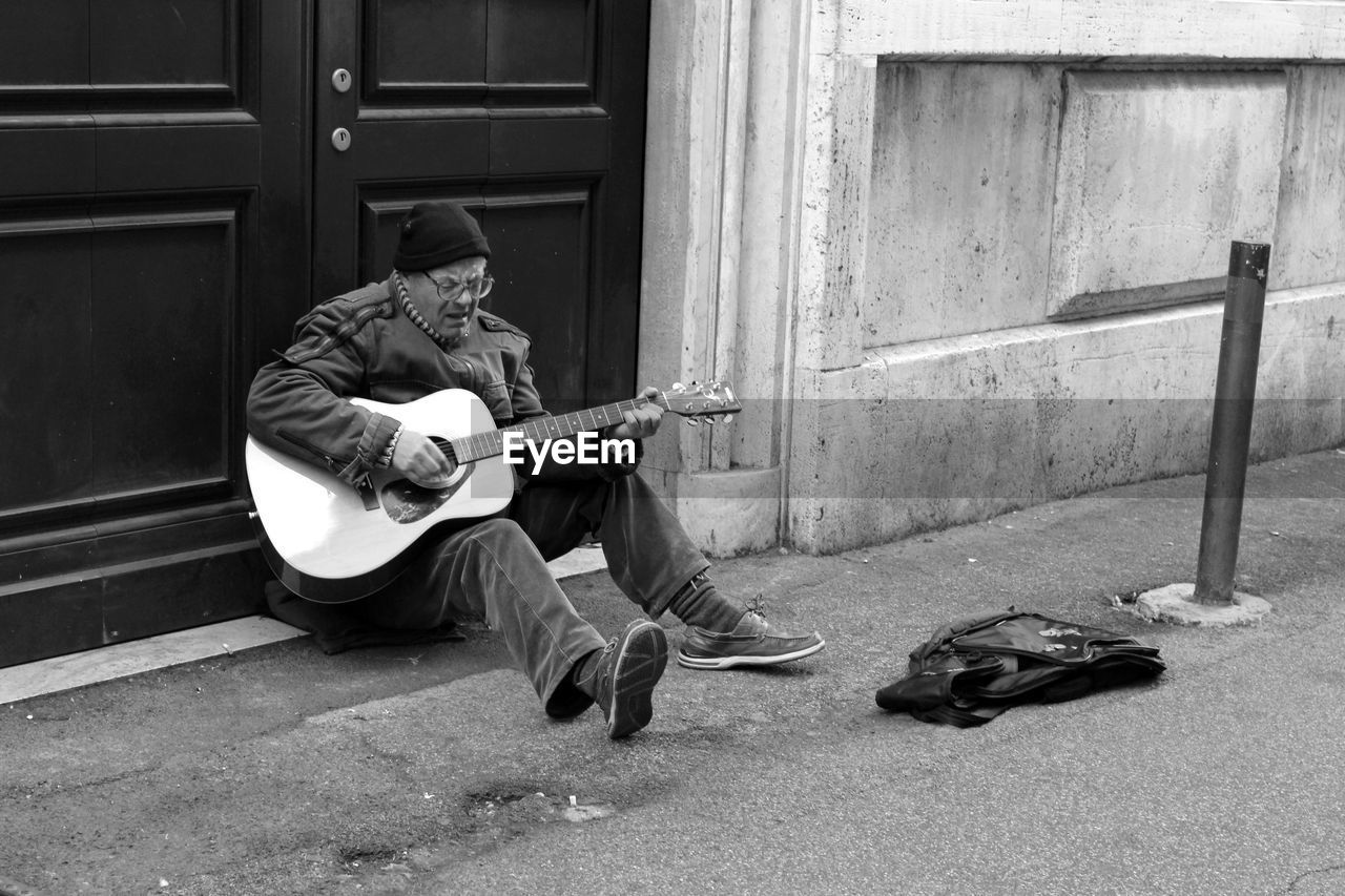 MAN PLAYING GUITAR ON THE GROUND