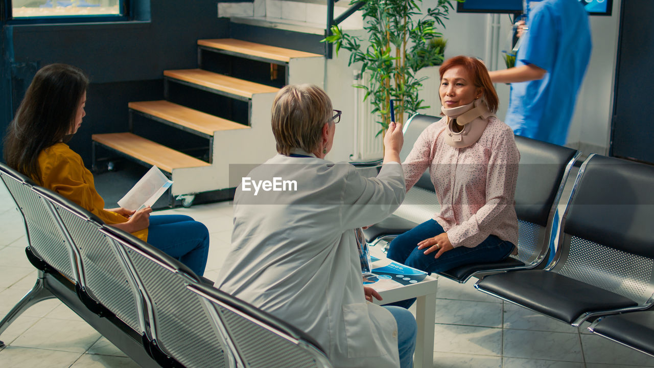 full length of female doctor examining patient in office