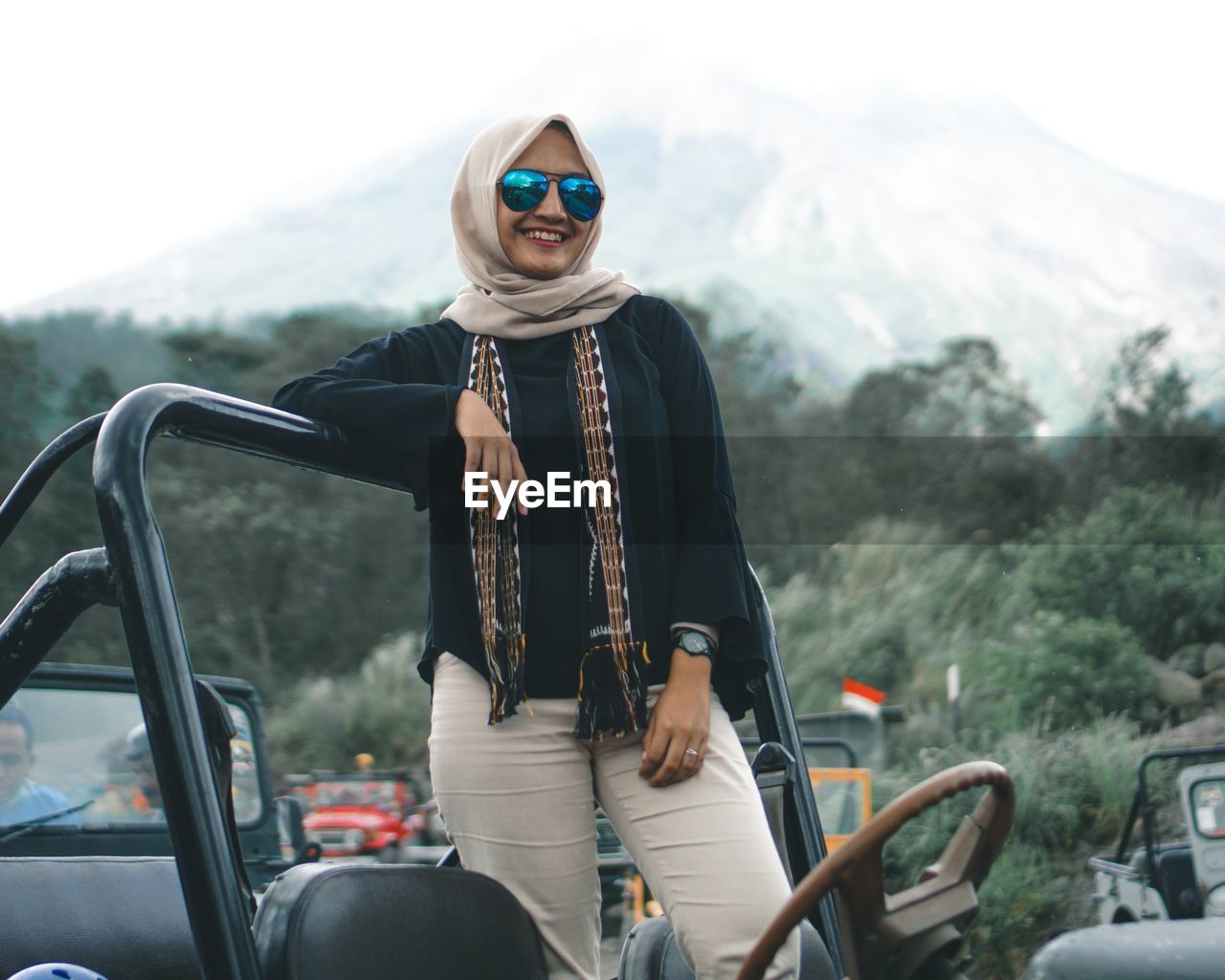 Woman riding jeeps car on road in front of mountain