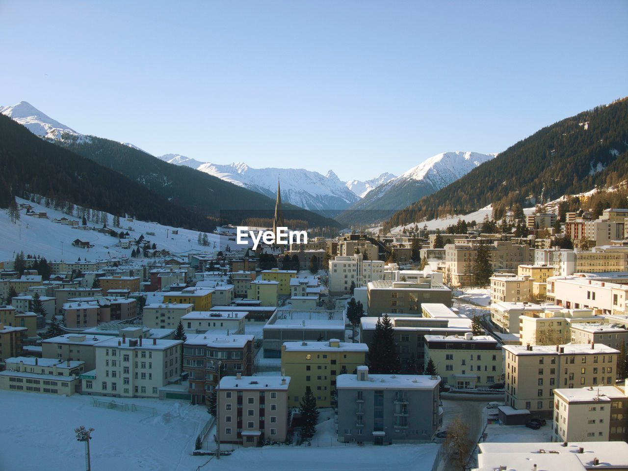architecture, mountain, snow, winter, building exterior, cold temperature, building, built structure, city, mountain range, sky, nature, landscape, environment, house, scenics - nature, residential district, travel destinations, town, travel, land, no people, clear sky, snowcapped mountain, beauty in nature, cityscape, village, blue, tourism, outdoors, high angle view, day, sunny, tree, sunlight