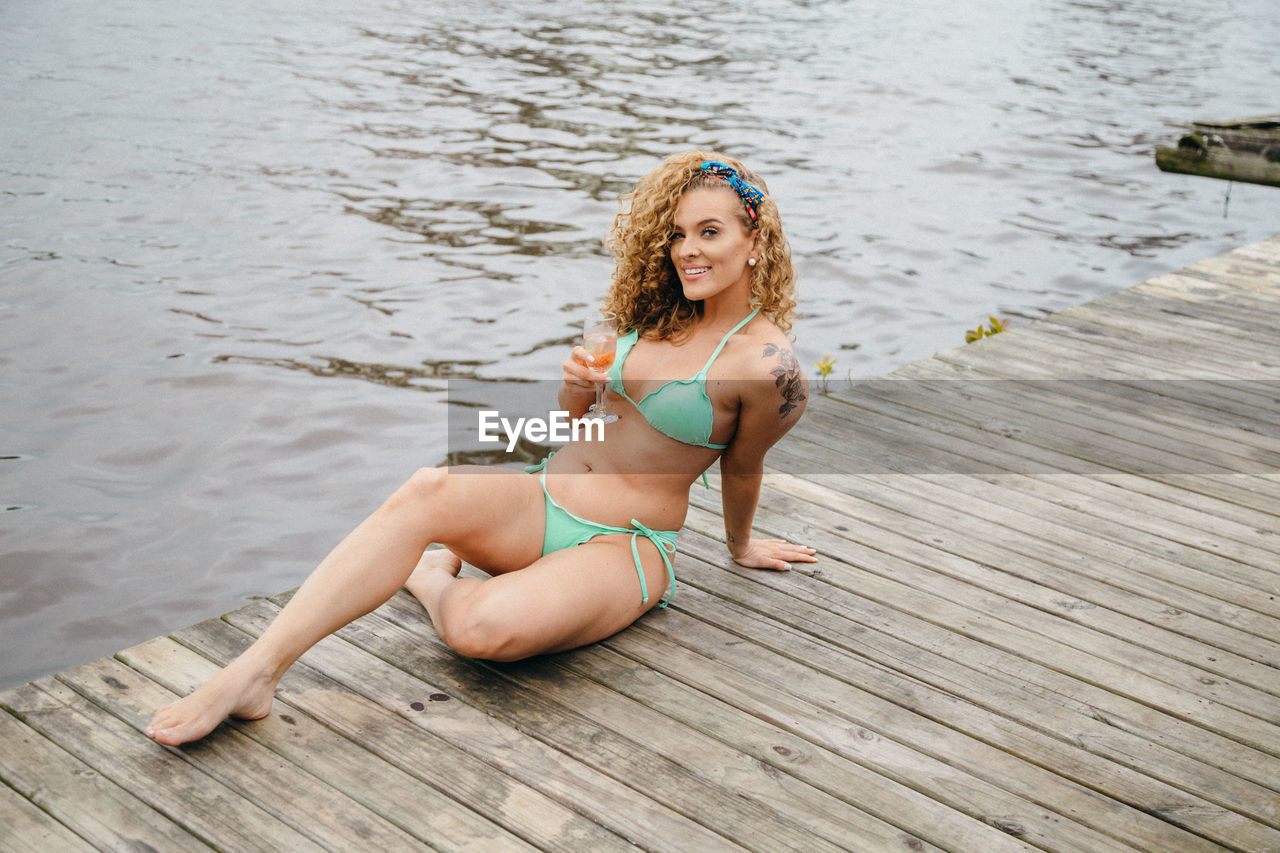 Young woman in bikini sitting on shore